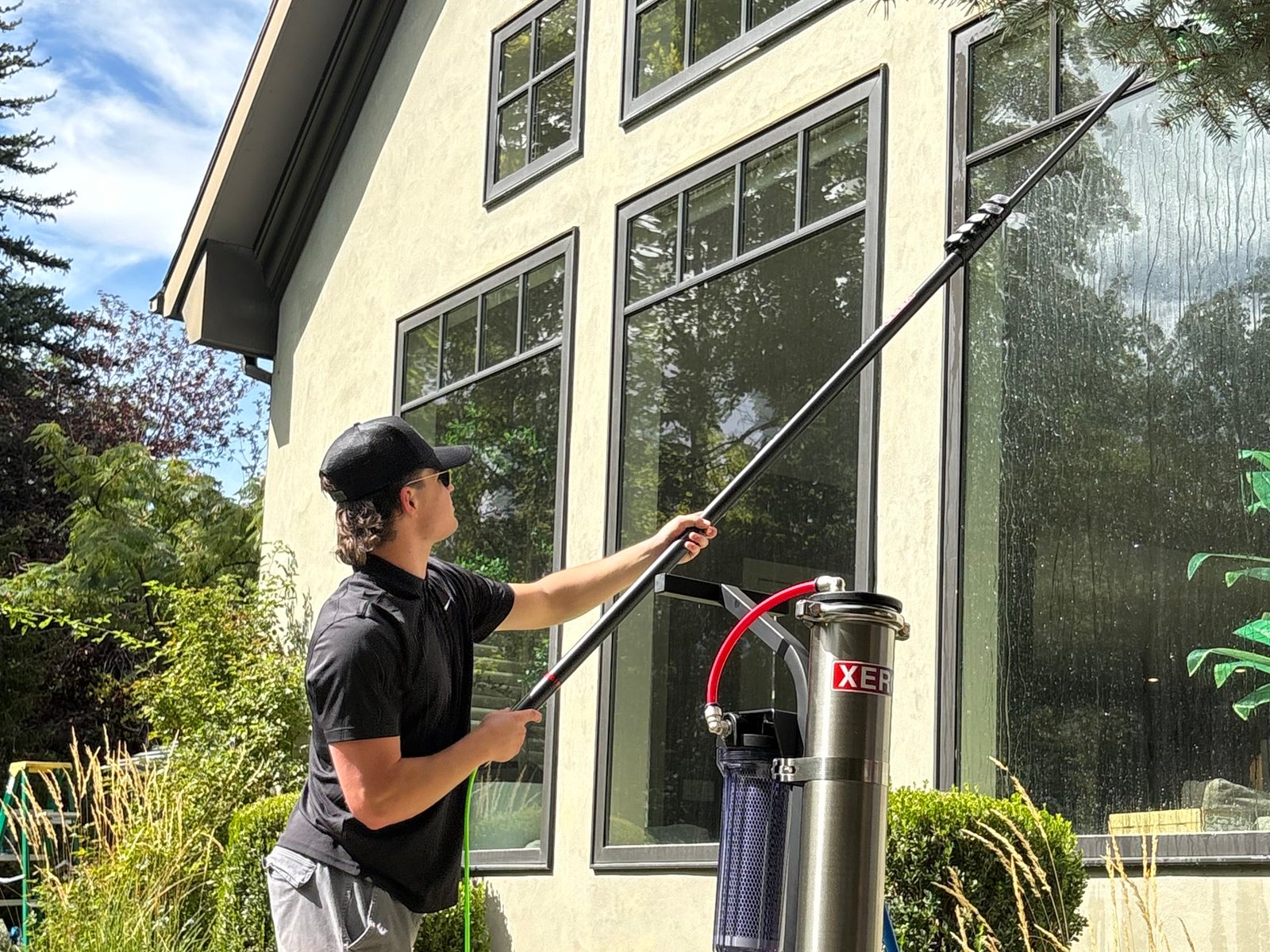 Brody cleaning tall second-story windows with a water-fed pole at a home in northern Utah